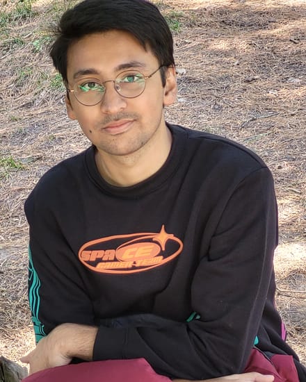 Sibte Hussain, sitting outdoors on a fallen log